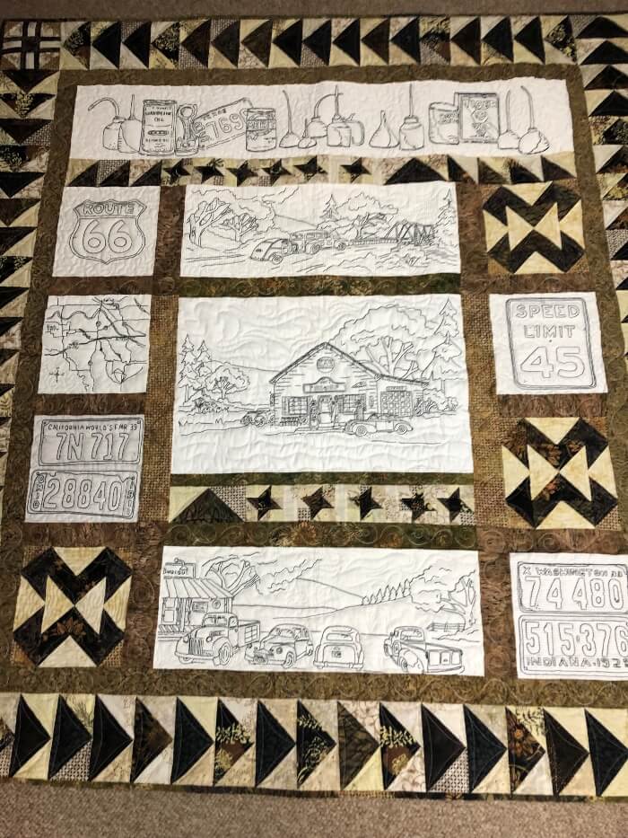 Quilt in tans and browns featuring quilted scenes of antique cars and memorabilia from Route 66